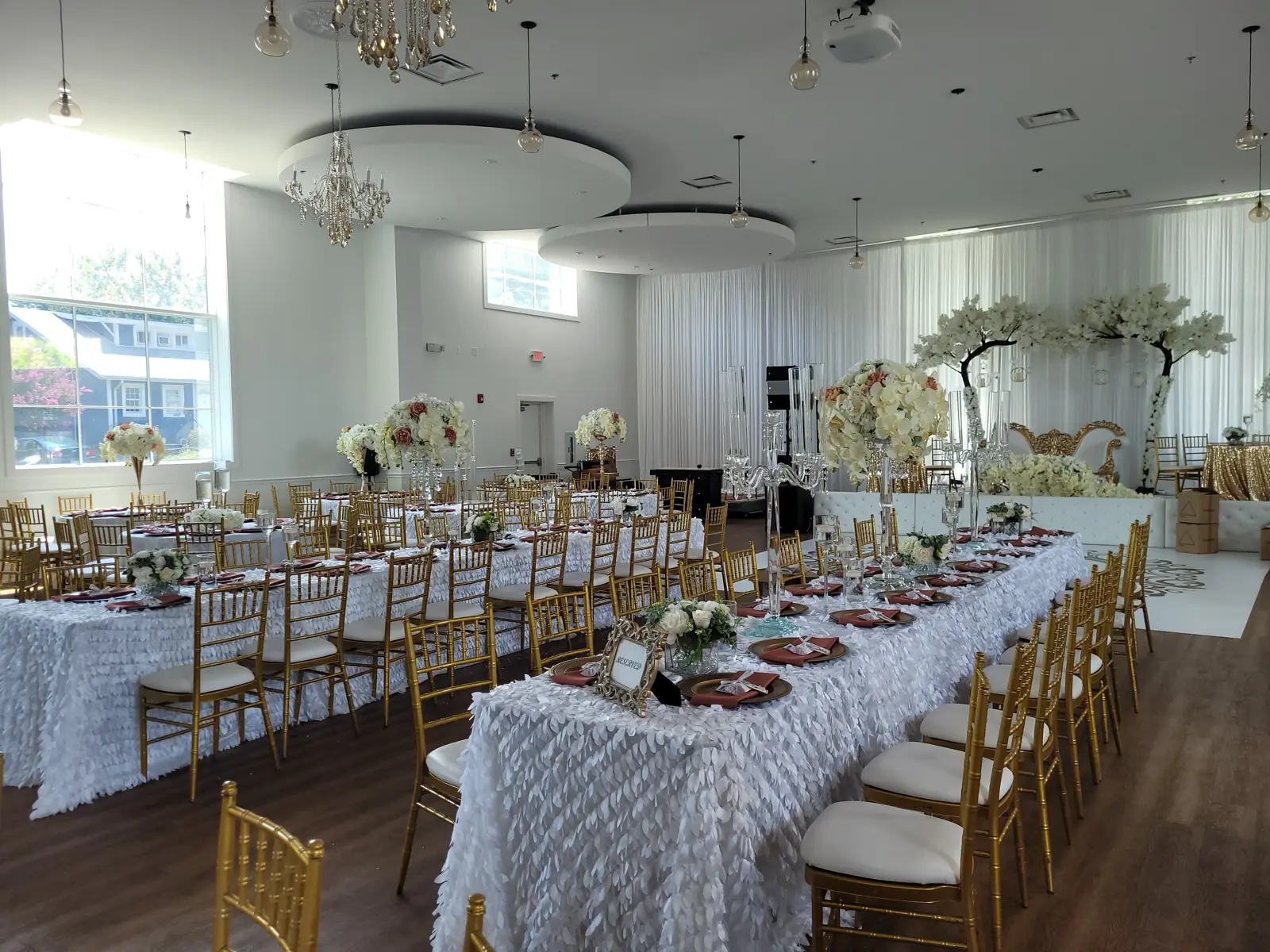 Side view of long banquet table with chandeliers, pendant lights, and cherry blossom trees